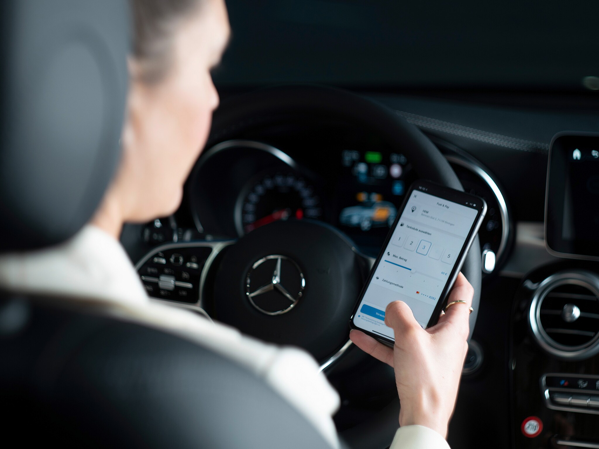 The image shows a woman using the Mercedes Me app on her smartphone.