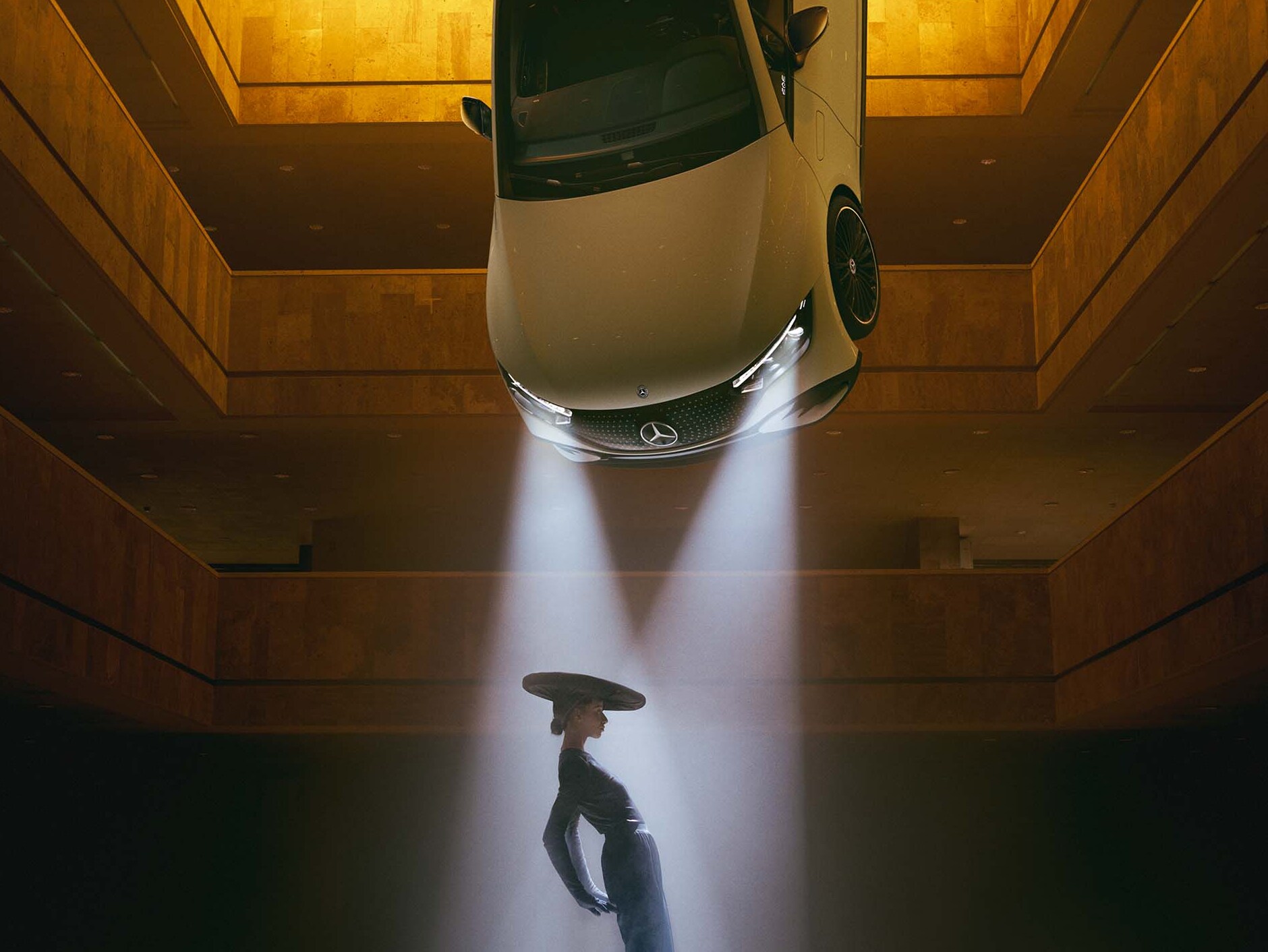 A dark room with spotlights hanging from the ceiling and a woman standing in the cone of light.