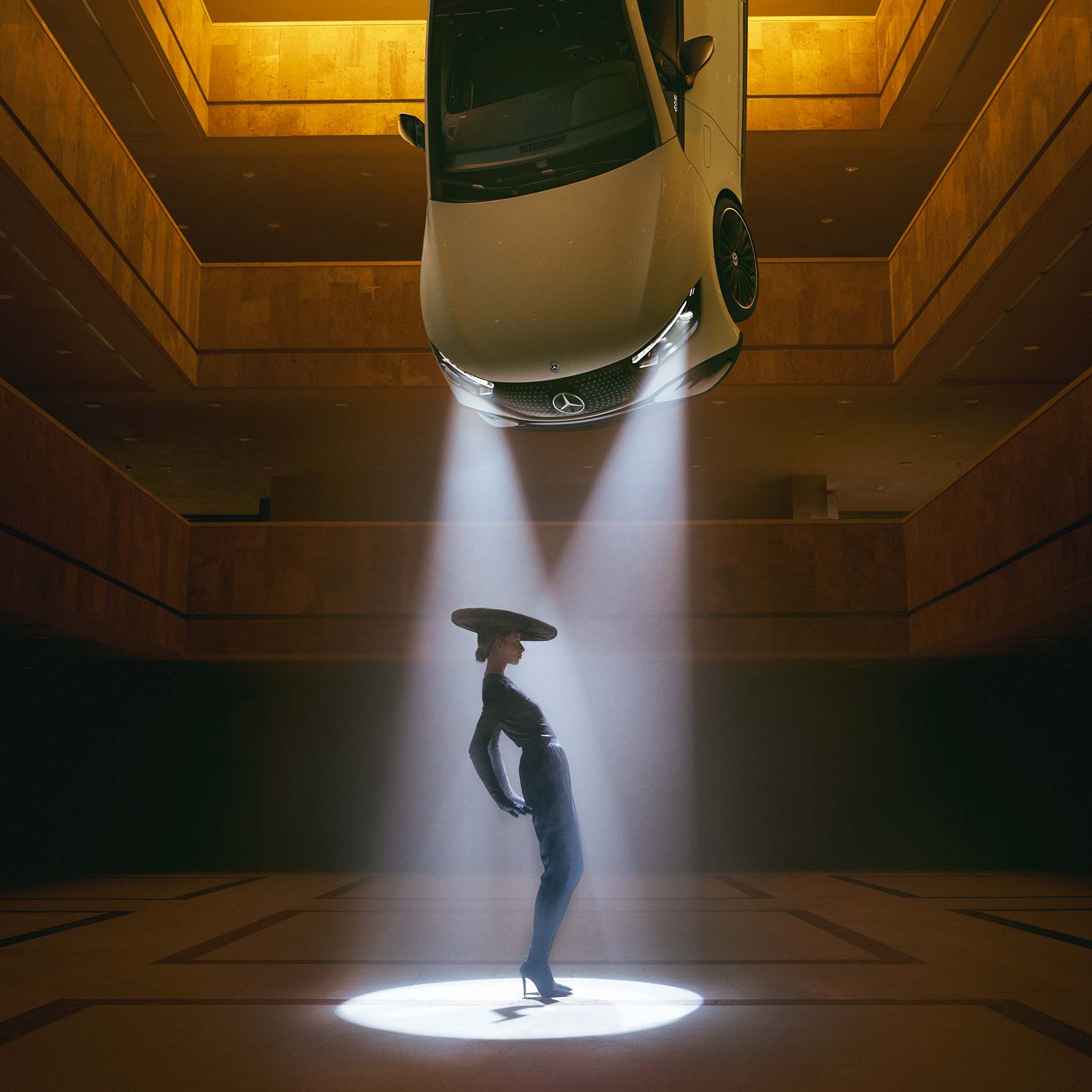 DIGITAL LIGHT illumination technology from Mercedes-Benz A dark room with spotlights hanging from the ceiling and a woman standing in the cone of light.