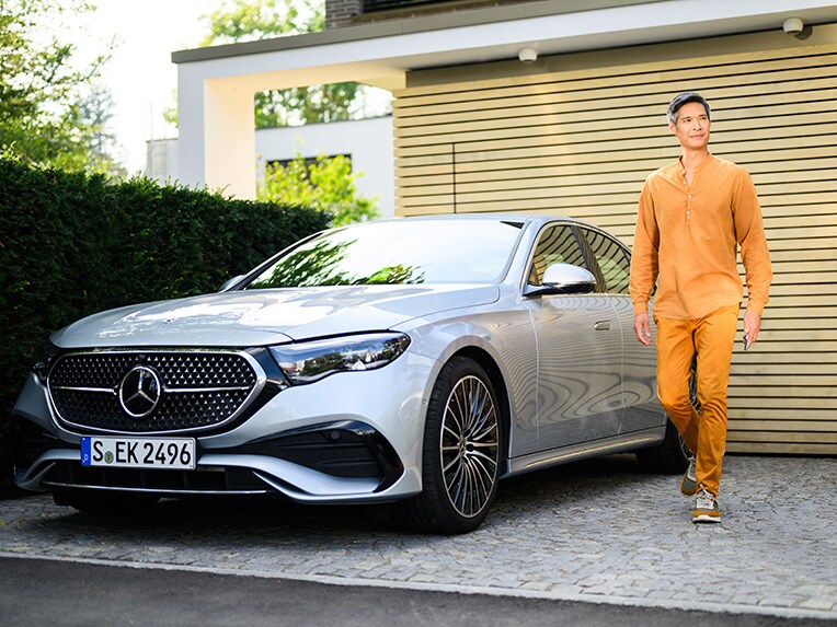 A person walking away from a Mercedes-Benz vehicle looking into the distance.