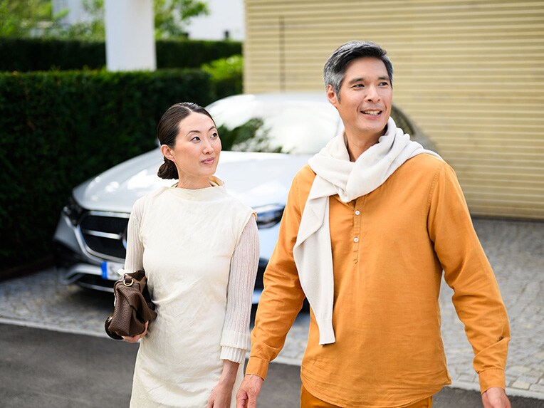 Two people walking away from a Mercedes-Benz vehicle and looking into the distance.
