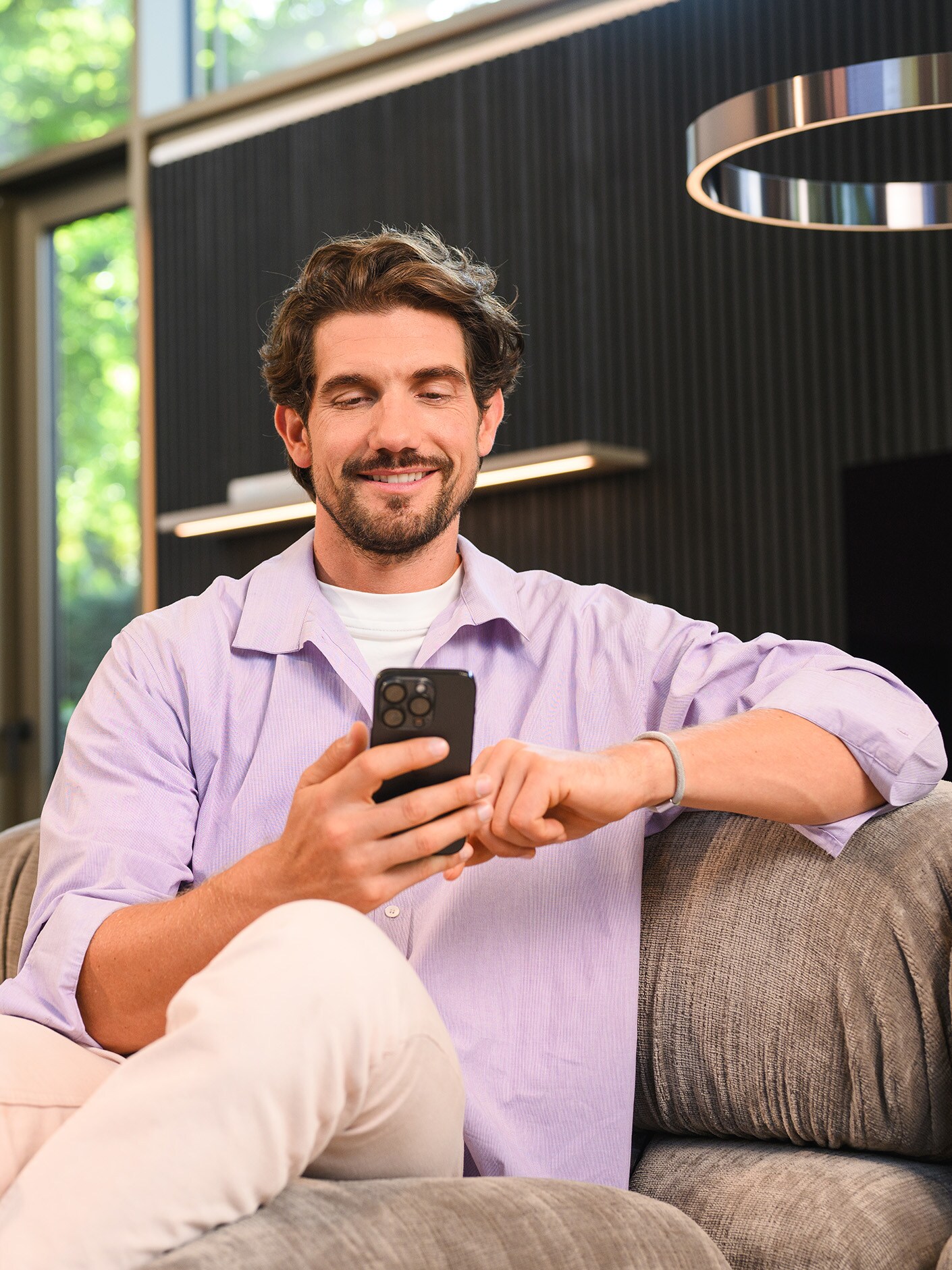 A person sitting on a sofa and using their mobile device.