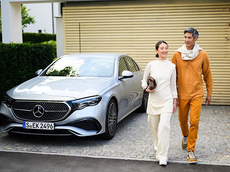 Two people walking away from a Mercedes-Benz vehicle and looking into the distance.