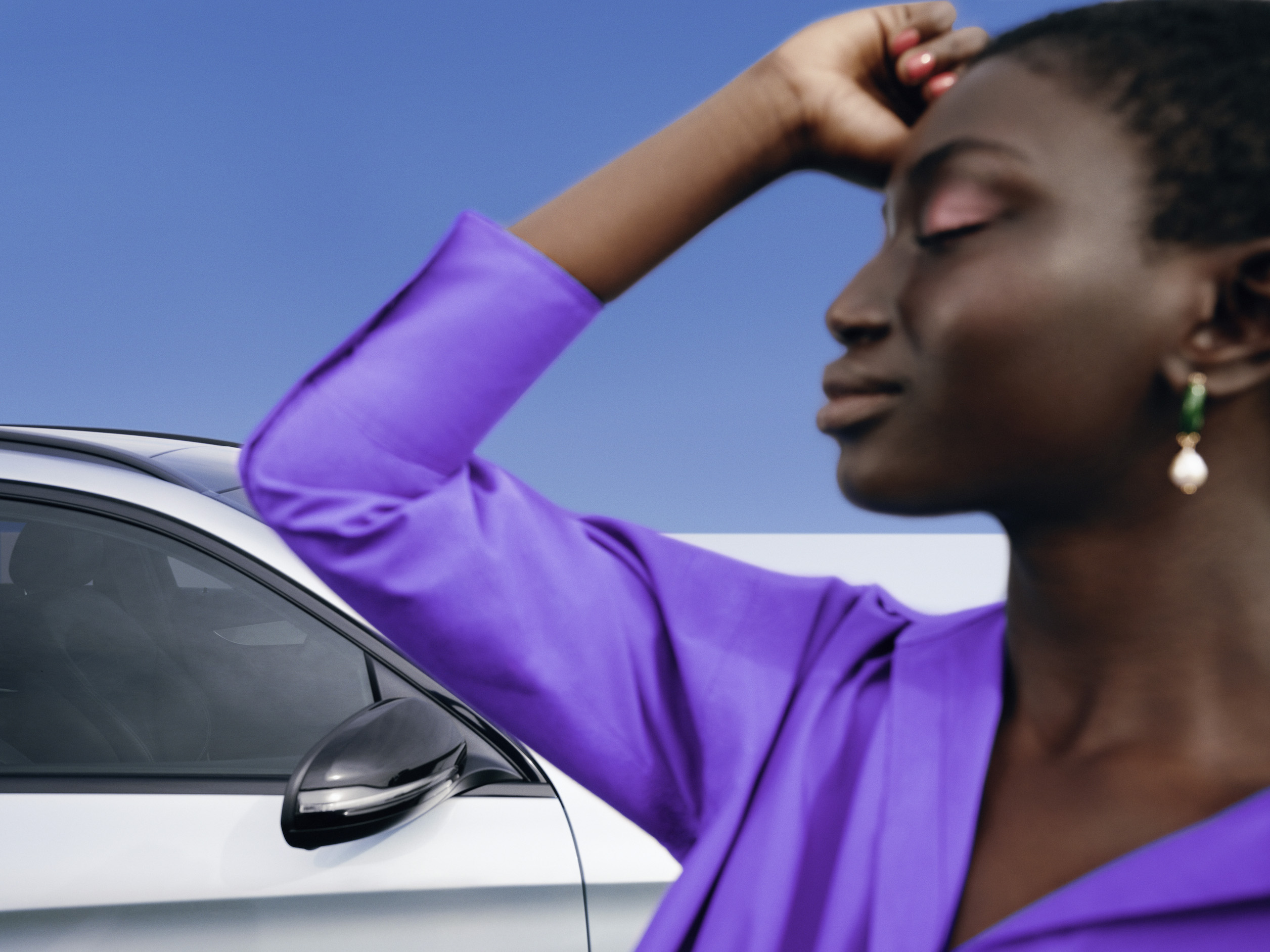 Mercedes-Benz | Genuine Car Care Products A woman standing relaxed in front of her Mercedes with an emotionless facial expression.