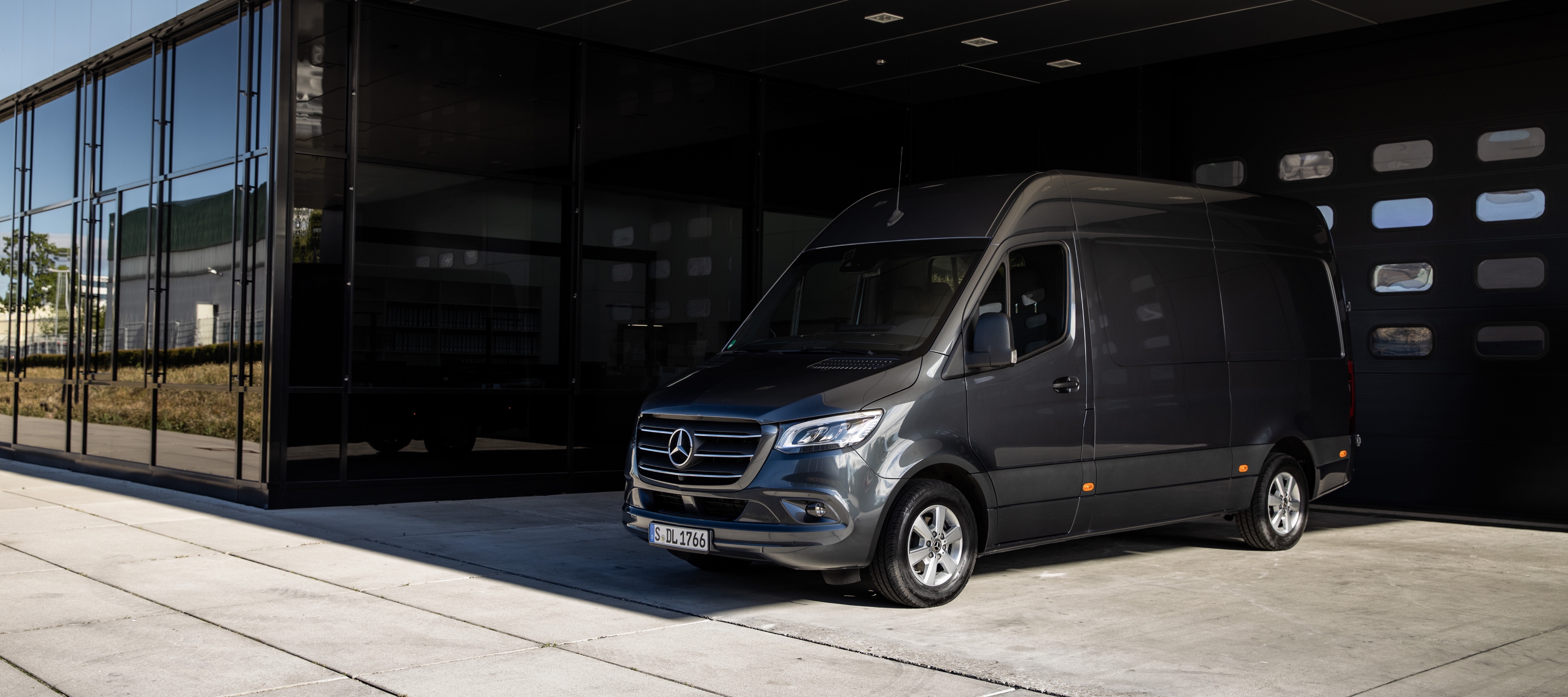 Sprinter Panel Van | Mercedes-Benz Vans A Sprinter Panel Van from Mercedes-Benz standing in front of a roll-up gate in a modern courtyard.