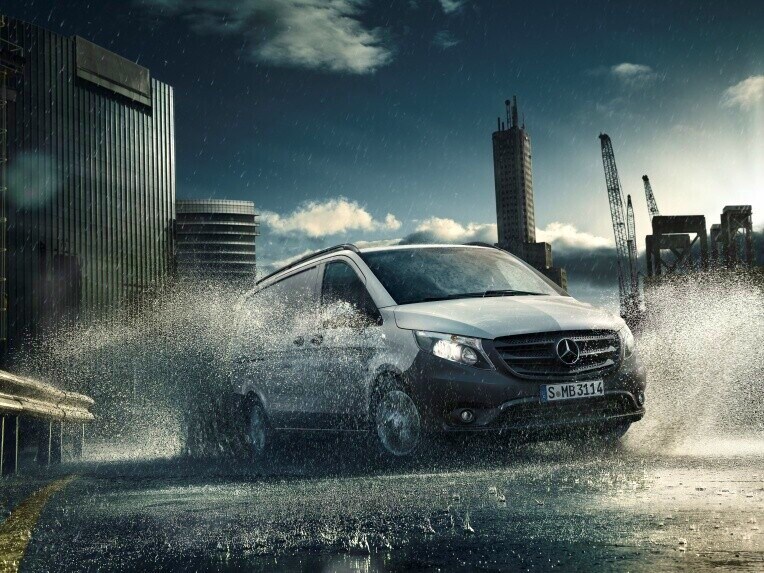 A Vito panel van from Mercedes-Benz driving through water in an urban landscape.